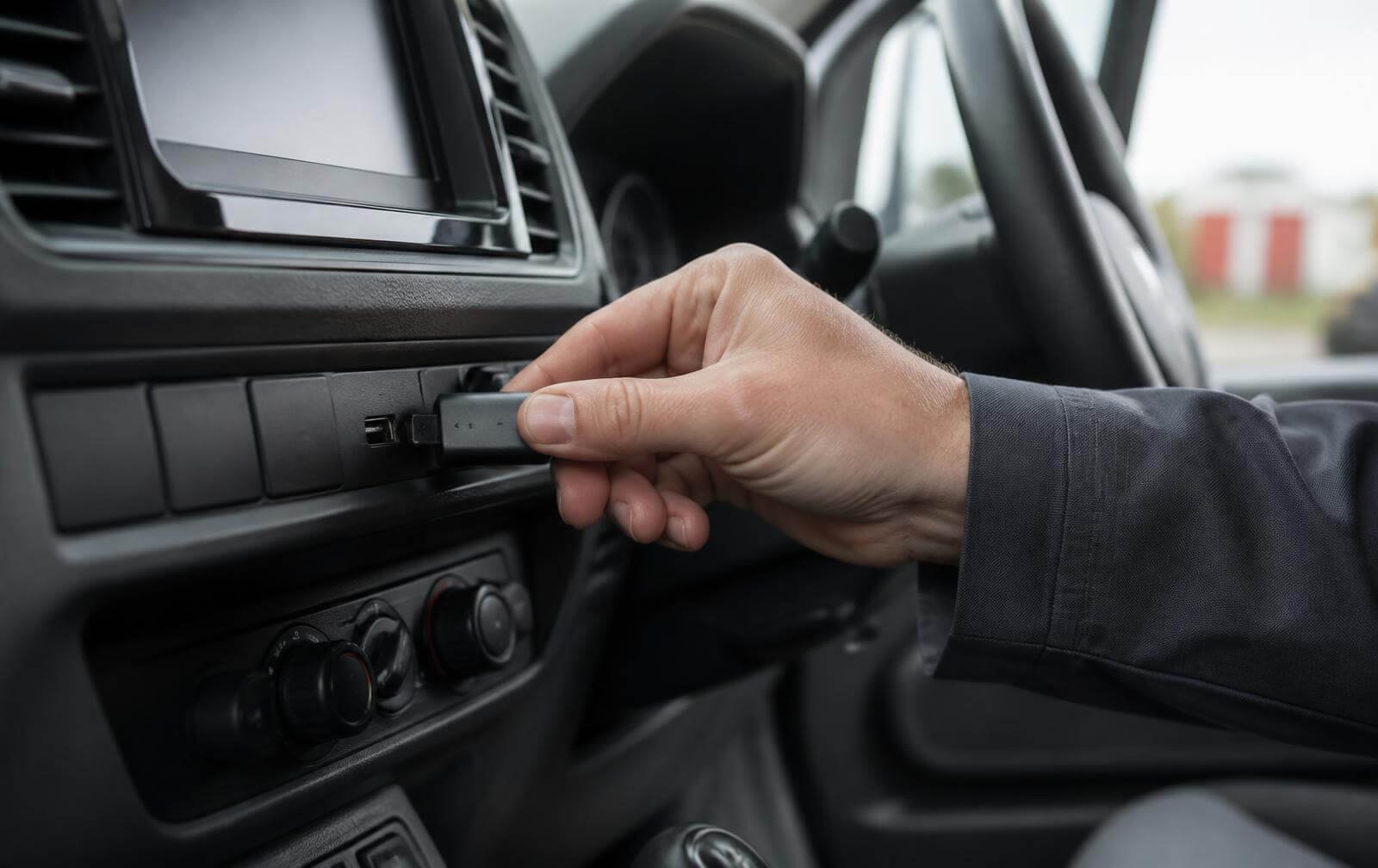 Hand plugging a small RangerPost USB tag into the USB socket of a commercial van